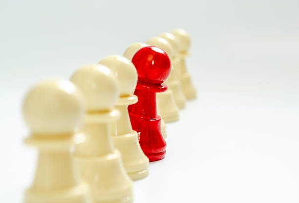 Standing red pawn breaking formation representing speaking up