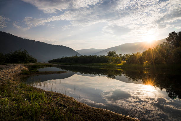 Sunrise over pond and mountains, summertime, Kootenays, B.C.