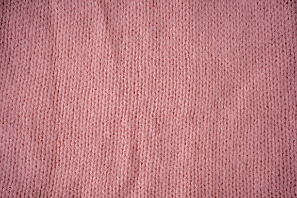 Pink and soft pastel woolen balls in basket with crochet hook