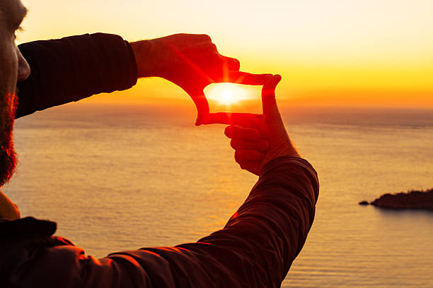 A man making photo frame with hands to photographing sunset