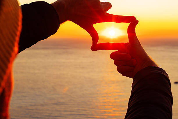 A man making photo frame with hands to photographing sunset