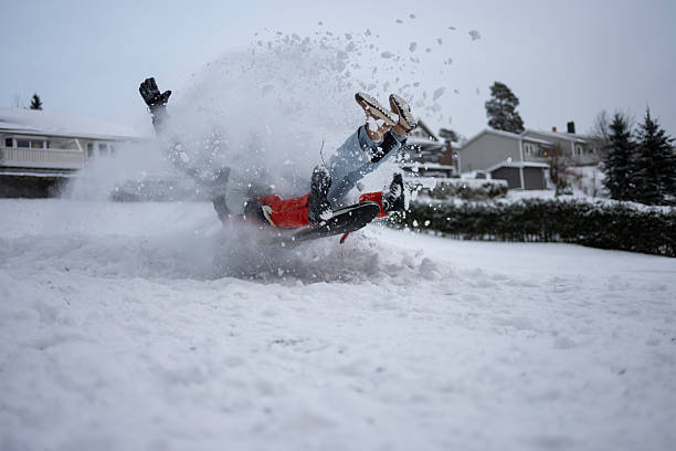 A man rides a blue sled downhill, captured in focus, while friends slide on colorful sleds behind him. The snowy landscape and bright winter jackets convey energetic outdoor fun.
