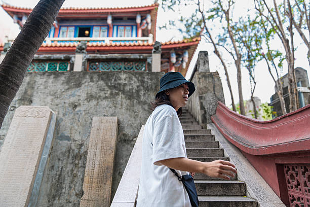 Man with bucket hat walking up temple stairs at ancient chihkan tower