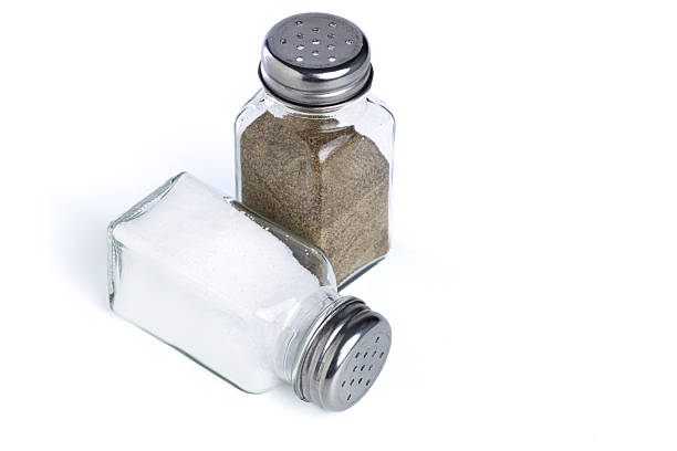 Glass salt and pepper shakers with metal caps isolated on white background. Seasoning, spices, cooking ingredients, kitchen essentials and minimal culinary still life