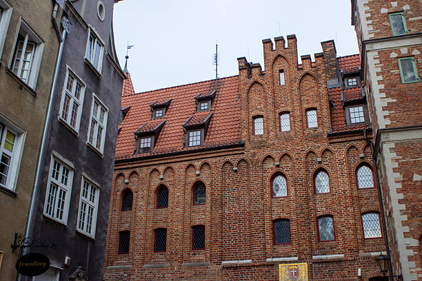 Gdansk, Poland. June 07, 2019. Historic brick building facade with Gothic architectural details surrounded by traditional old town houses in the city center.