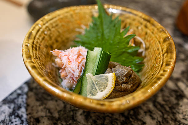 Close-up of a Japanese-style crab appetizer featuring fresh crab meat and crab roe, served in a ceramic bowl with sliced cucumber, lemon, and shiso leaf. Elegant presentation highlighting traditional Japanese cuisine and fine dining culture.
