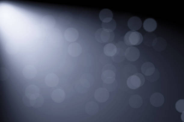Minimalist dark grey and black abstract background with a dramatic spotlight beam and blurred bokeh effects. Ideal for corporate layouts, luxury product displays, and sleek tech-themed designs with ample text space.