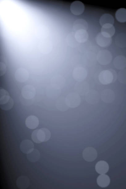 Minimalist dark grey and black abstract background with a dramatic spotlight beam and blurred bokeh effects. Ideal for corporate layouts, luxury product displays, and sleek tech-themed designs with ample text space.