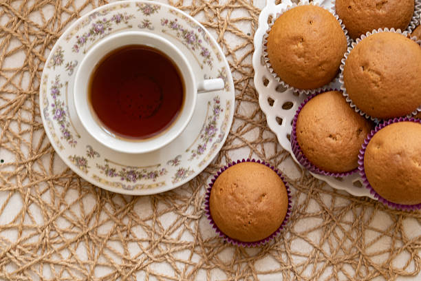 Cup of tea and a plate of muffins in the background. Breakfast.