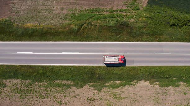 Aerial view of an old red fire truck driving fast on a highway, captured from a drone perspective, symbolizing emergency response, speed, and public safety. Directly above.
