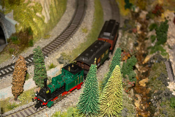 Toy train set displayed in a detailed miniature landscape with tracks, greenery, and scenery. Ideal for model railway, hobbies, toys, educational content, and creative photography. Perfect for backgrounds, lifestyle, and playtime concepts