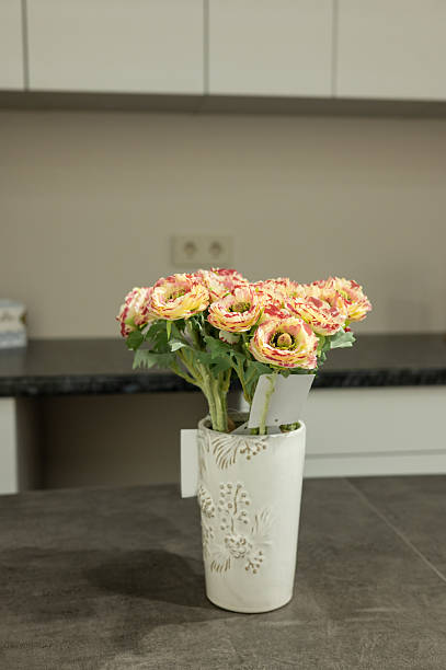 Elegant bouquet of pink and yellow flowers in decorative vase on kitchen counter