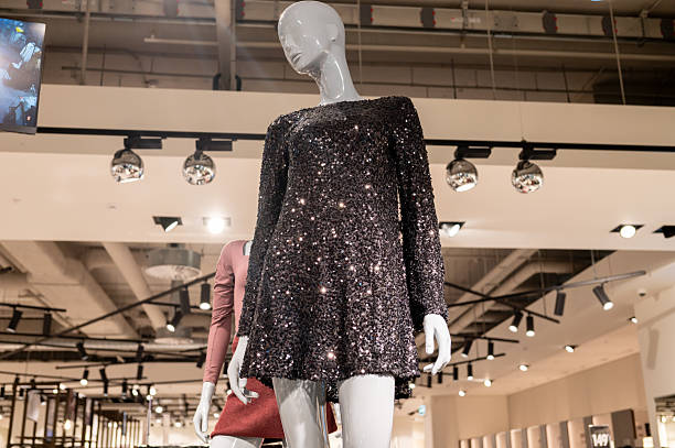 Mannequin showcasing an elegant red dress with a gold belt in a boutique window, highlighting fashion and style