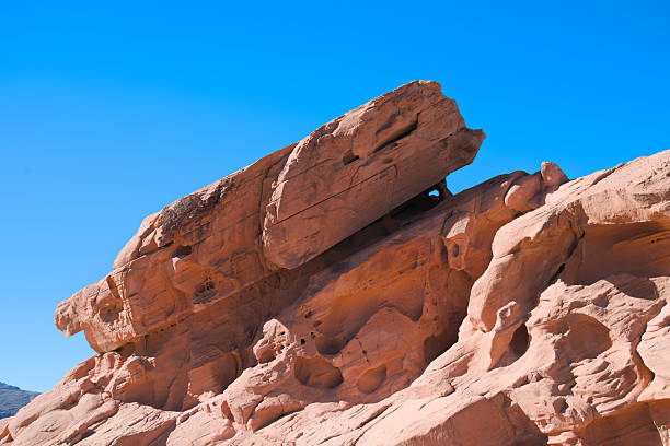 An angled sandstone outcrop displays weathered surfaces and erosion patterns in the Bowl of Fire area of Lake Mead National Recreation Area under bright desert light.