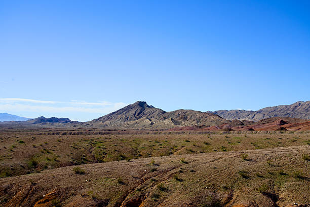 An arid desert valley stretches toward rugged mountain ranges in southern Nevada, emphasizing open space, dry conditions, and natural desert landforms.