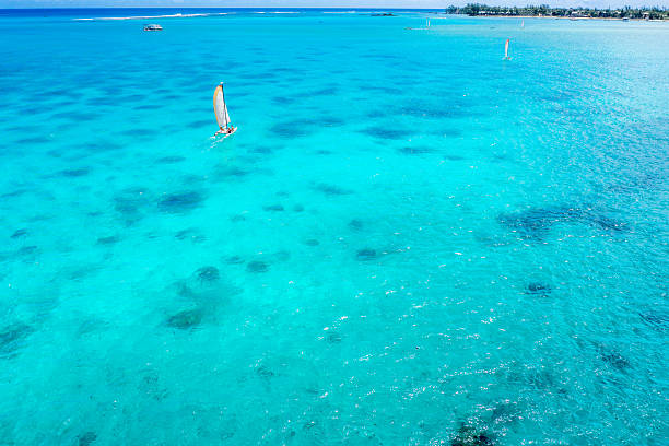 Catamaran sailing in crystal clear turquoise water, aerial view, Mauritius