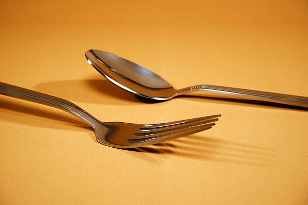 Conceptual image of decision making where a hand chooses a spoon over a fork. Minimal simple living style on white background with Copy Space symbolizing evaluation, preference and everyday decisions.
