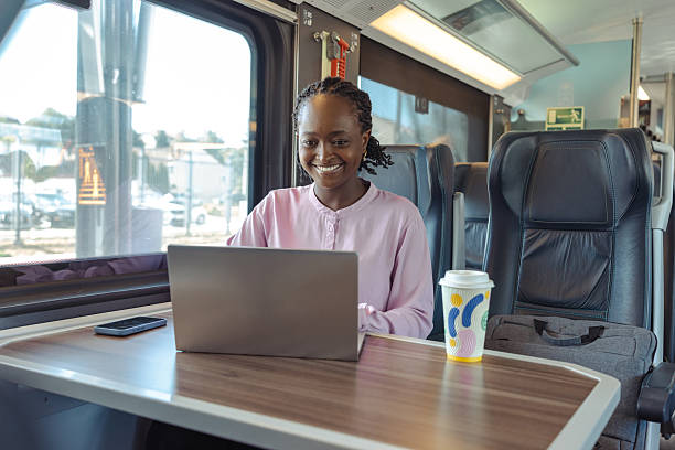 istock Young woman on train working on laptop with coffee cup during commute 2259447587