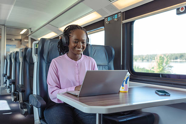 istock Young woman smiling while working on a laptop on a train during her daily commute 2259447836