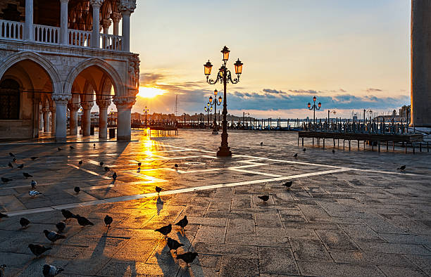 Early morning sunrise at Piazza San Marco with golden light, long shadows, and quiet atmosphere after night.