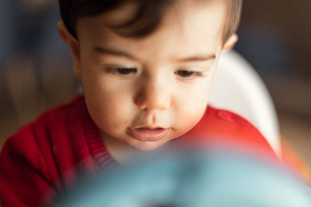 A close-up shot of a baby focused intently on a toy, with a blurred background for effect.