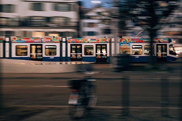 Zurich, Switzerland – January 23, 2026: Panning shot of a ZVV branded VBZ tram moving through Zurich with strong motion blur and city buildings in the background.