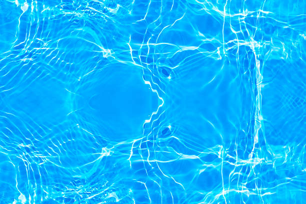 Blue swimming pool water, with waves, and reflections from sunlight