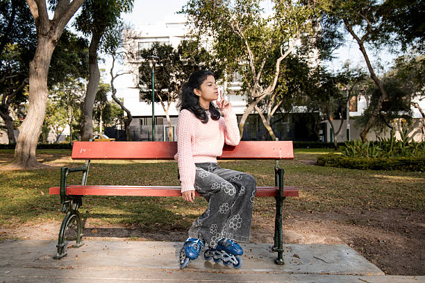 Plastic cup filled with cola, left on wooden park bench.