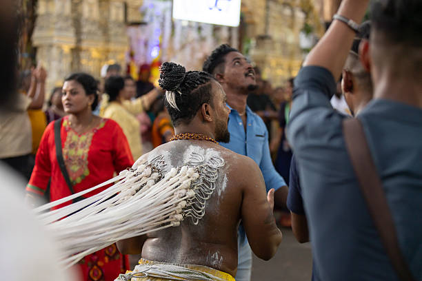 01 February 2026, George Town - Penang Island.Young Tamil man takes part in the Alagu Kuthuthal piercing ritual, with hooks attached to his back and tied to ropes that are pulled from behind. Even with the strong resistance, he continues walking toward the temple, showing determination, endurance, and personal devotion as part of Thaipusam practices.