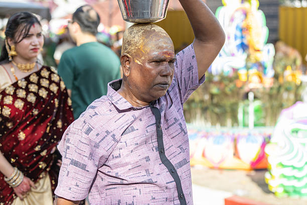 01 February 2026, George Town - Penang Island.A middle-aged devotee with a shaved head carries a kavadi during the Thaipusam festival, with turmeric paste applied on his scalp. The turmeric paste symbolizes purification, blessing, and the fulfillment of a vow as part of his devotion to Lord Murugan.