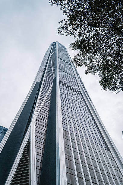 Modern futuristic architecture of a silver skyscraper against a cloudy sky in China business district.