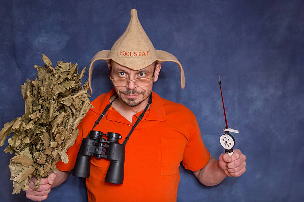 A funny man with a bath broom and a fishing rod in his hands.
