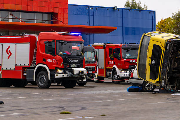 Kalisz, Greater Poland Voivodeship, Poland - October 08, 2025 line of emergency response vehicles coordinates at a simulated accident scene. Firefighters use professional equipment to stabilize an overturned Jelcz truck and perform victim extrication.