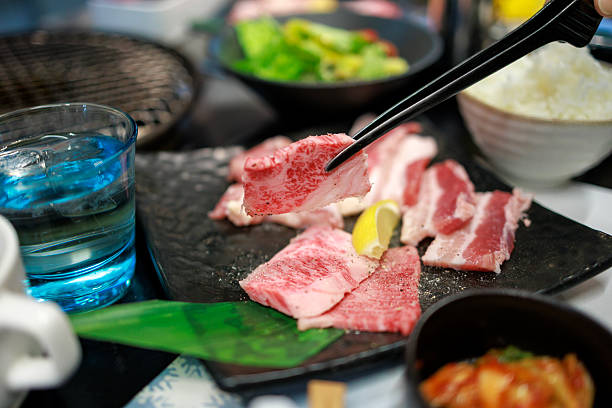 Wagyu Beef Slice Picked with Chopsticks at Japanese Barbecue Table