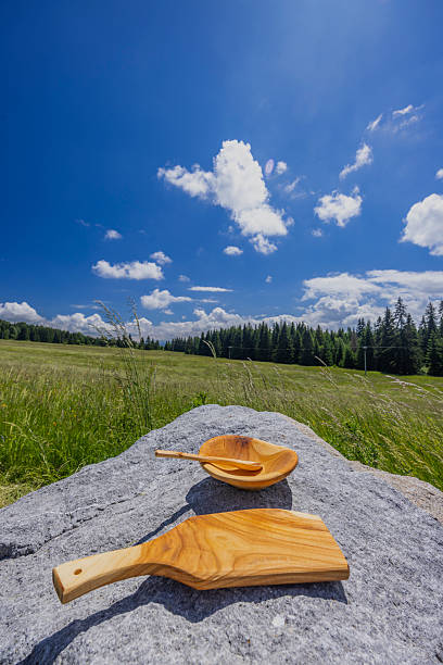 Handcrafted wooden kitchenware on rock by green meadow