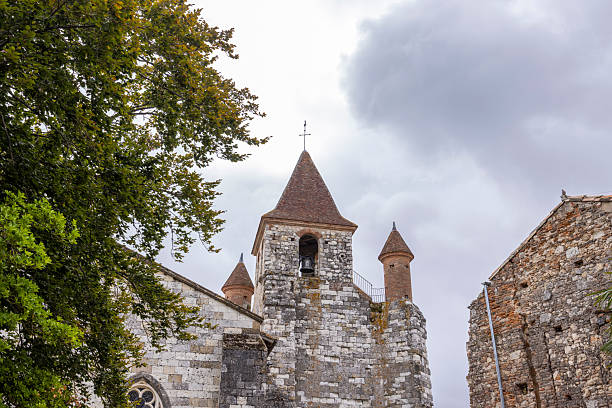 Auvillar church bell tower showing historic stone architecture and traditional tile roof under cloudy sky