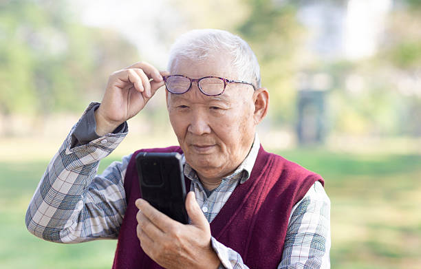 Poor Eyesight. Senior  Man Using Smartphone Wearing Eyeglasses