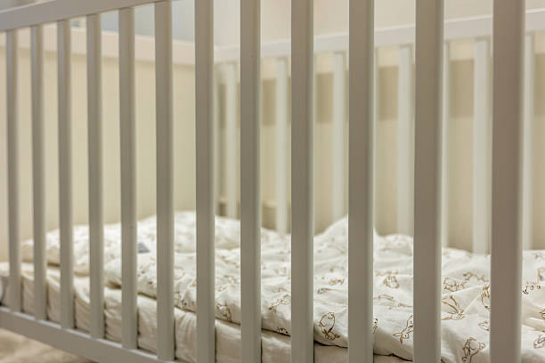 White slats and light patterned bedding create a calm nursery mood. A preparation concept for newborn life aligned with nursery and hygge trends.