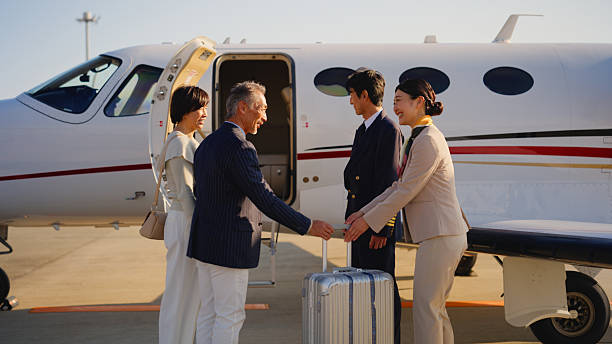 A senior couple is walking to their private jet and meeting with the cabin crew and greeting each other.