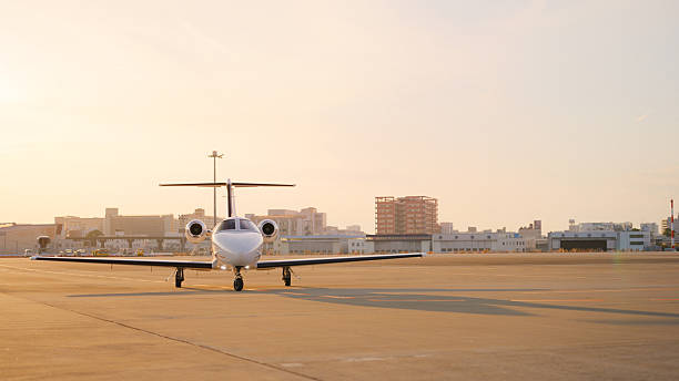 A private jet at an airport runway during sunset.