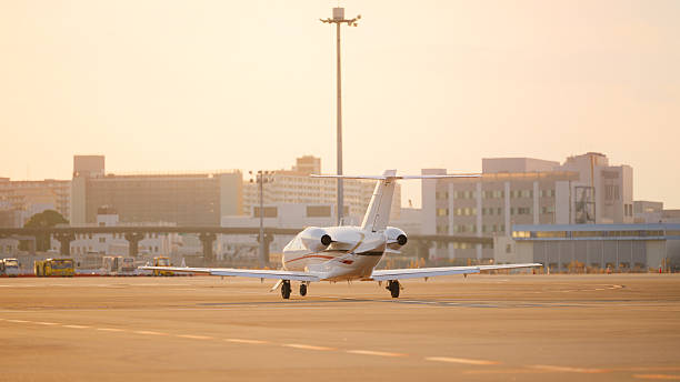 A private jet at an airport runway during sunset.