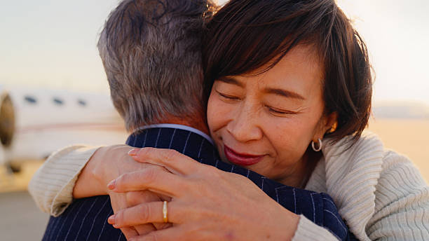 A close-up portrait of a senior couple hugging and showing love for each other next to a private jet.