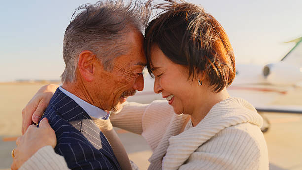 A close-up portrait of a senior couple hugging and showing love for each other next to a private jet.
