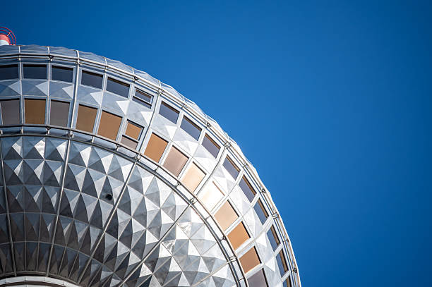 Berlin, germany, august 11, 2023. Berlin tv tower's geodesic sphere features windows and geometric paneling, standing against a clear blue sky, demonstrating modern architecture