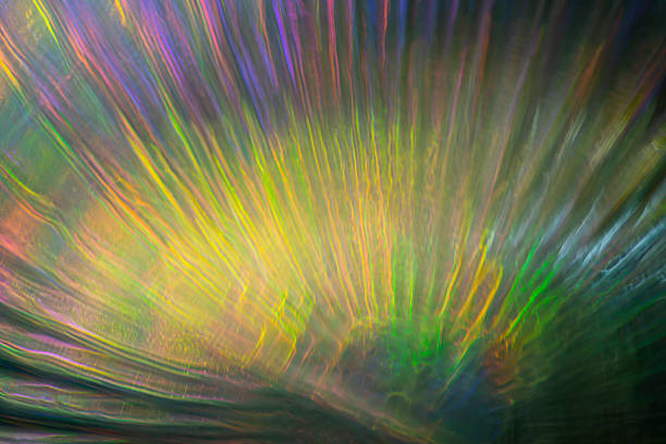 Golden, green, and violet light streaks flare outward in long exposure, creating an abstract field of motion that evokes emotion, warmth, and inner energy.