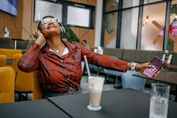Black woman enjoying listening music at work while on a coffee break