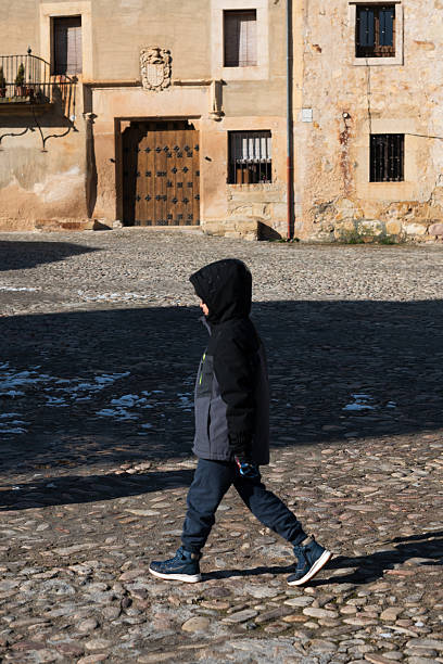 Child walking alone on a cobblestone street in a historic European town square