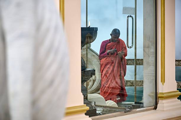 Reflection of a monk inside a temple in Ella, framed by ornate golden architectural elements.