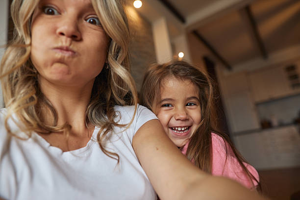 Mother and daughter enjoying playful bonding while making funny faces for a selfie