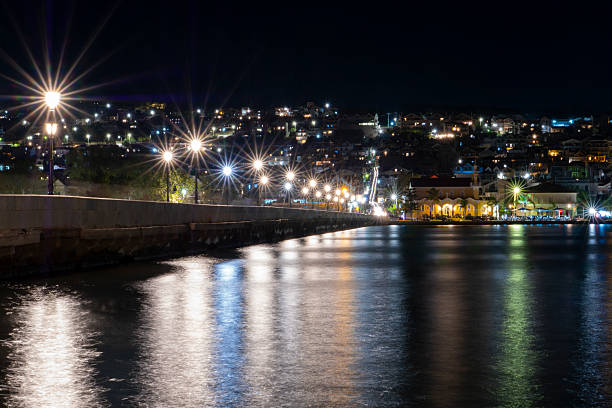 Night view of Argostoli waterfront in Kefalonia, Greece, with city lights reflecting on calm water, showcasing a peaceful coastal cityscape and urban nightlife atmosphere.